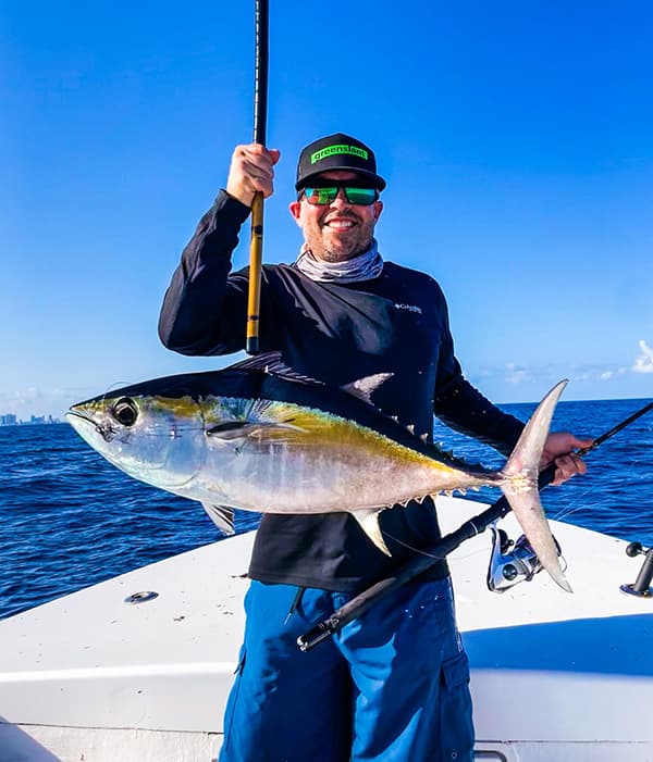 Matthew Howe holding a blackfin tuna on a boat offshore from Haulover Inlet, Florida